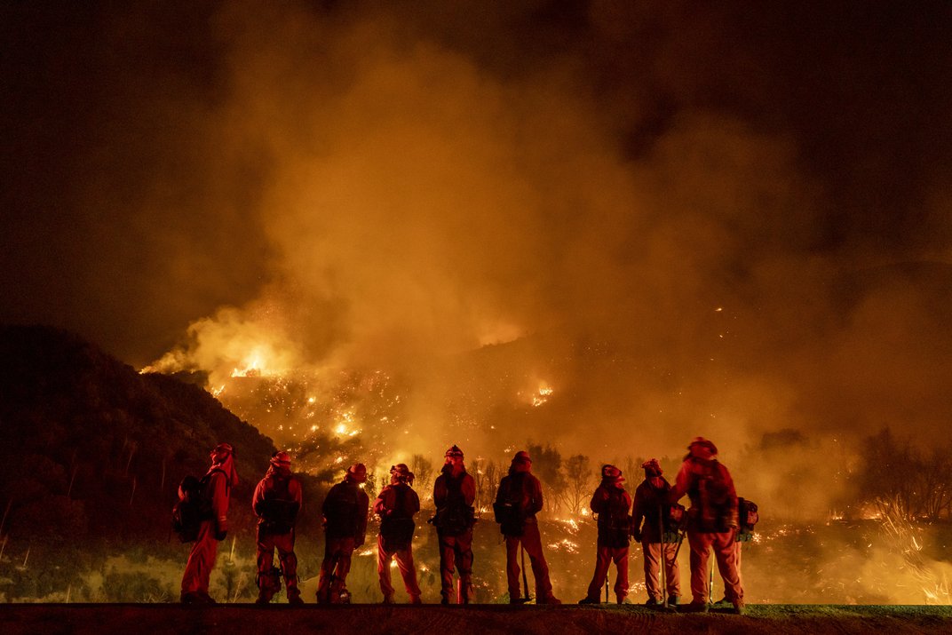 A group of inmate firefighters watches as the El Dorado Fire burns a hillside near homes in Mountain Home Village, California, on September 9, 2020.
