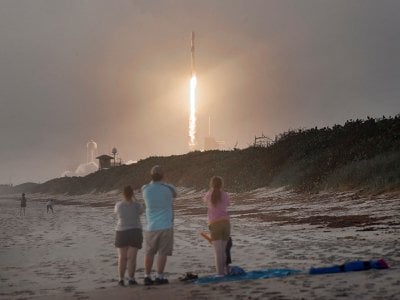 Spectators watch from Canaveral National Seashore as a SpaceX Falcon 9 rocket carrying 60 Starlink satellites launches.