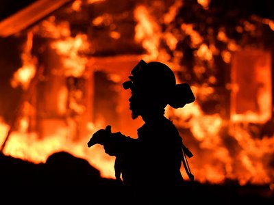 An inmate firefighter monitors flames as a house burns in the Napa wine region of California on October 9, 2017.