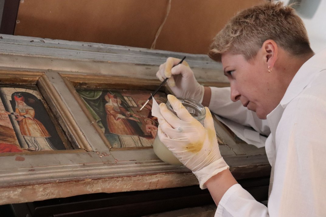 A conservator infills a painted panel during a museum visit